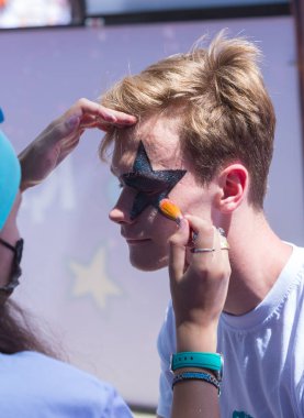 Almatı, Kazakistan - 10 Haziran 2018: Tanımlanamayan kız makyaj sanatçısı bir parlak karnaval yüz boyama Almatı Arena stadyum yakınında Yarkokros partisinde festival katılımcılara 10 Haziran yapar