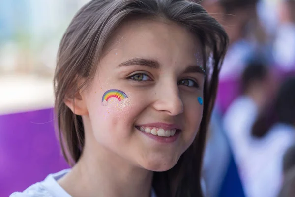 ALMATY, KAZAKHSTAN - JUNE 10, 2018: Unidentified girl makeup artist makes a bright carnival face painting to the festival participants at the Yarkokros party near the Almaty Arena stadium on June 10 — Stock Photo, Image