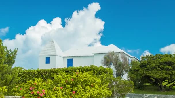 原始的百慕大房屋建筑在一个田园活力百慕大设置 具有白色混凝土墙和屋顶结构包围的热带树叶与白云在蓝天 — 图库视频影像