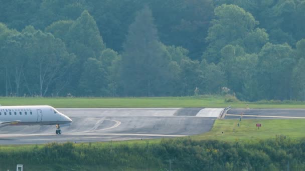 ユナイテッド航空エクスプレスジェットは 誘導路から滑走路に旋回し 西ノースカロライナ州の山岳地帯の夏の日の日没時にアッシュビル地域空港Avlから離陸の準備をしています — ストック動画