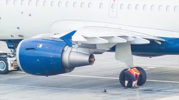 民間旅客機の車輪からブレーキブロックを取り外す空港地上支援作業員 — ストック動画
