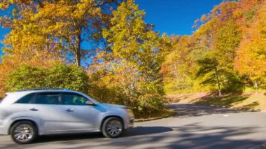 Kuzey Carolina'da Büyükbaba Dağı yakınlarındaki Blue Ridge Parkway'de Bir Karşılama Merkezi'nde Sonbahar Renkli Ağaçlar Geçen Araç Mavi Gökyüzü ile Sonbaharda Güneşli Bir Günde