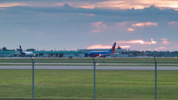 傍晚在路易斯 阿姆斯特朗新奥尔良国际机场与西南航空公司商业客运喷气式客机在充满活力的日落彩色天空背景前交通 — 图库视频影像