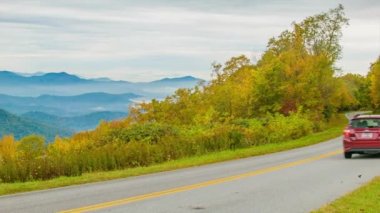 A Red Vehicle Asheville Nc yakınlarındaki Beautiful Blue Ridge Parkway Üzerinde Sürüş Sonbaharda Arka Planda Dumanlı Dağların Mavi Katmanları ve Ön Planda Sonbahar Yaprağı Renkleri Tonları ile