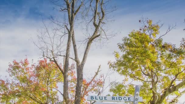 倾斜到怀旧蓝岭公园路标志附近的阿什维尔在西部北卡罗来纳州的烟雾山脉与秋天的彩色叶子和蓝天背景 — 图库视频影像
