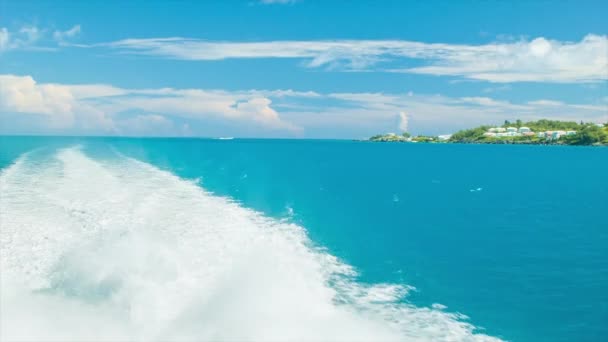 牧歌的な日にバミューダの熱帯の島の近くの海に白い水を飛び散らして目を覚ますボート — ストック動画