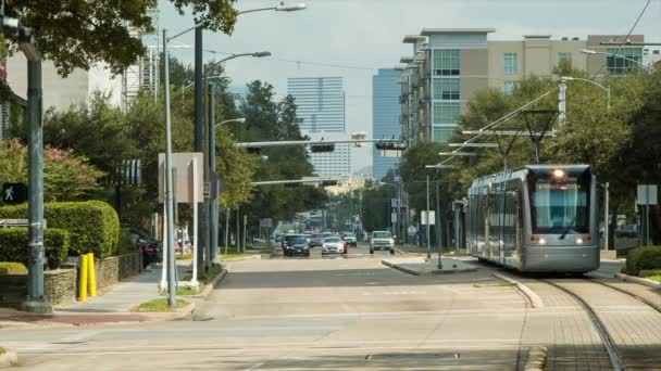 地铁轻轨公共交通驾驶在休斯敦市博物馆区的街道上与其他汽车和车辆经过一个车站在德克萨斯州的阳光日 — 图库视频影像