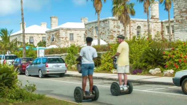 游轮乘客游客享受赛格威游览在热带百慕大群岛在阳光明媚的一天与绿色棕榈树 历史建筑和蓝天 — 图库视频影像
