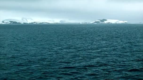 从在冰冻的南极洲海洋中航行的船舶在穆迪天气与冰冰山拍摄与较低的成分 — 图库视频影像
