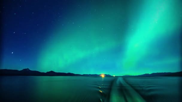 オーロラオーロラボレアリスは アラスカのフィヨルドで澄んだ星で満たされた青い夜空を横切って踊る緑の形成と海の移動船から見た — ストック動画