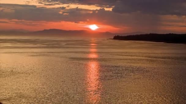 地平線上の山々とオレンジの太陽からの黄金の水の反射と海の上の壮大なアラスカ日没日の出 — ストック動画