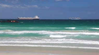 Bir Petrol Tankeri ve Kargo Gemisi Güney Afrika Cape Town Harbor giriş bekliyor. Dalgalar Dan Sadece Off-shore bir Shipwreck Close-by ile Plaj üzerine Su Breaking görülür.