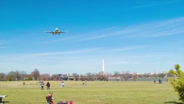 ワシントンDcのグレイブリーポイントパークを楽しむ人々は 旅客機が頭上を飛び 記念碑を背景に飛んで — ストック動画