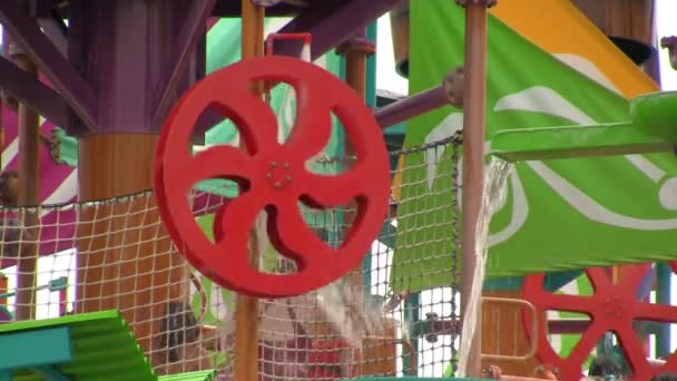 Ein Sich Drehendes Rotes Wasserrad Mit Unkenntlich Gemachten Wasserparkbesuchern Dahinter — Stockvideo