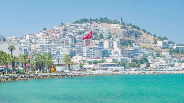 晴天時の山の丘に対する建物と旗を持つクサダシトルコの活気に満ちた海辺の設定のトルコのリゾート先 — ストック動画