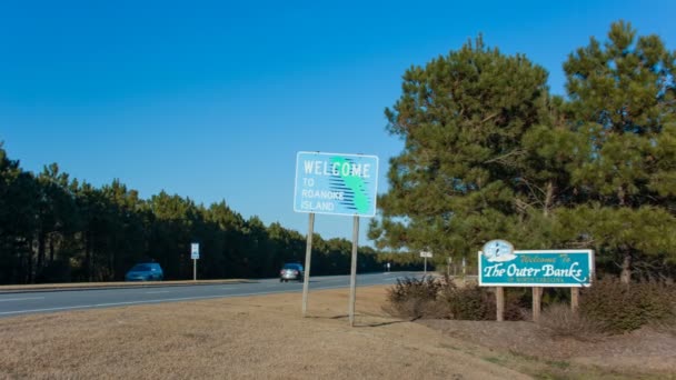 ノースカロライナ州のローノーク島外岸へようこそ 晴れた午後の道路標識を通り過ぎる車 — ストック動画