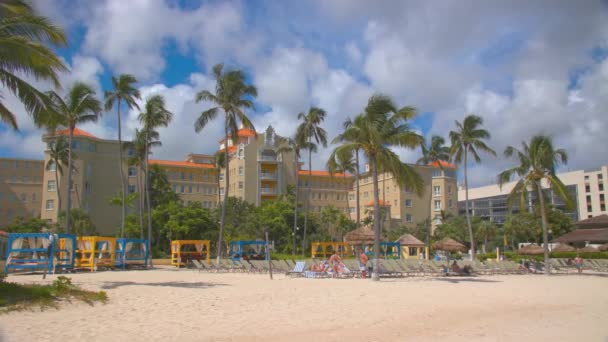 拿骚巴哈马英国殖民地希尔顿海滨度假村场景与游客享受棕榈树和海滩伞在标志性的巴哈马地标酒店前的充满活力的设置 — 图库视频影像