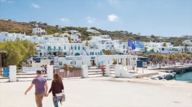 Güneşli Akdeniz gününde beyaz binalar içeren şehre gelen turistler ile Yunanistan 'da Mikonos Adası 'na hoş geldiniz