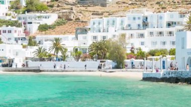 Hava Larda Beyaz Okyanus Kıyısındaki Evler ve Binalarla Sahil Boyunca Yürüyen Turistlerle Mikonos Yunanistan'daki Doğal Yunan Adası Sahnesi