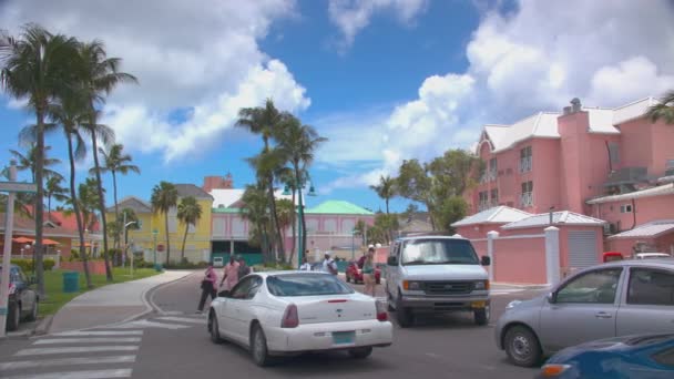 ナッソー バハマ パラダイス アイランド ストリート シーン 車の交通とエキゾチックな色の建物に囲まれたアトランティス リゾートで横断する人々 — ストック動画