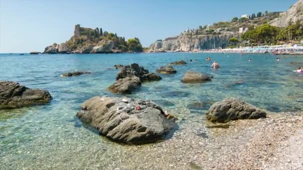 タオルミーナシチリアイタリア島海岸イソラベラで 夏の観光シーズン中にクリアブルー地中海のビーチで岩と小石を持つ — ストック動画