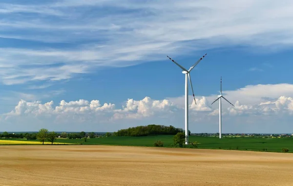 Wind power plant in a field on a background of blue sky and white clouds