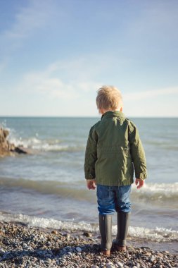 Çocuk sahilde dalgalar çökmesini izler