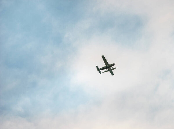 Single engine airplane flies across partially cloudy sky