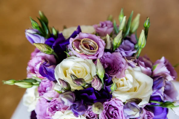 Wedding gold rings on a bouquet of flowers — Stock Photo, Image