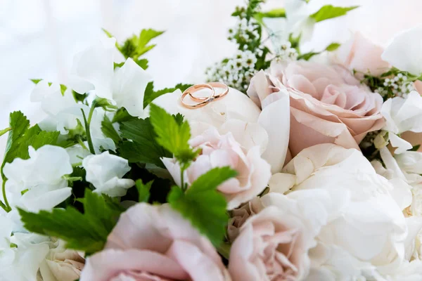 Goldene Eheringe an einem Blumenstrauß — Stockfoto