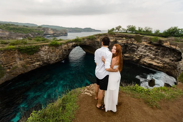 Jovem casal em um penhasco em frente ao oceano — Fotografia de Stock