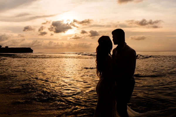 Recém-casados na praia ao pôr do sol — Fotografia de Stock