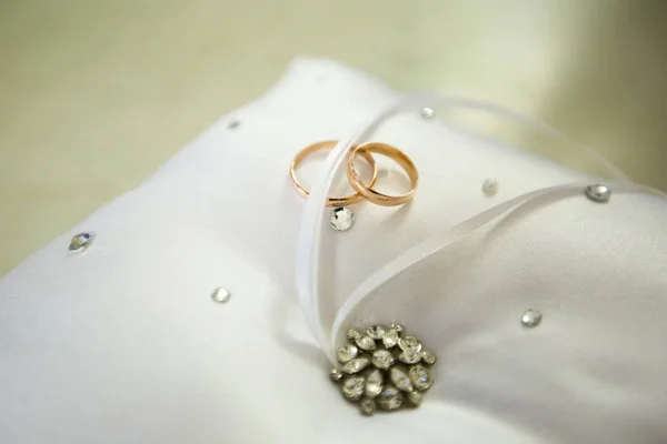 Un par de anillos de boda en una almohada blanca — Foto de Stock
