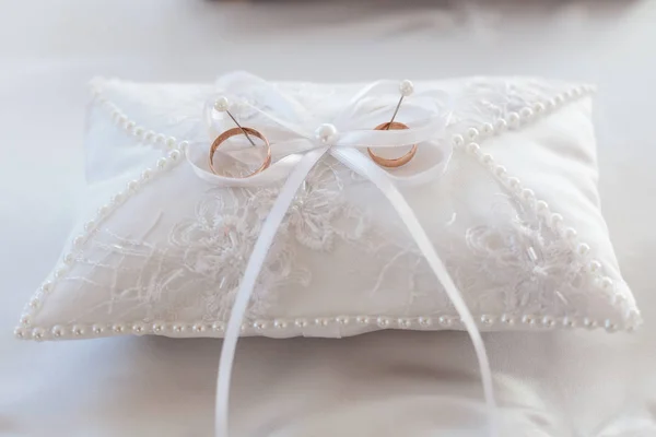 Un par de anillos de boda en una almohada blanca — Foto de Stock