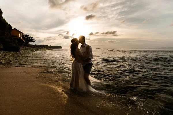 日落时一对年轻夫妇在海滩上 — 图库照片