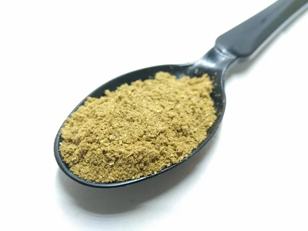 A picture of coriander powder on a black spoon