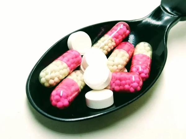 Picture White Tablets Red Capsules Black Spoon — Stock Photo, Image