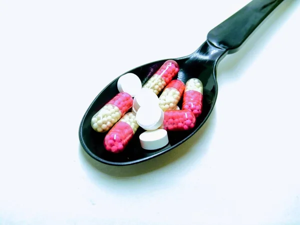 Picture White Tablets Red Capsules Black Spoon — Stock Photo, Image