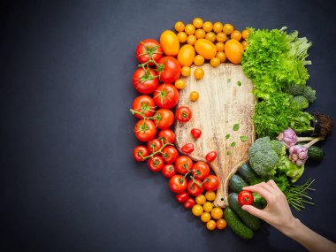 Boş rustik kesme tahtası siyah masada çeşitli renkli sebzeler ile çevrili