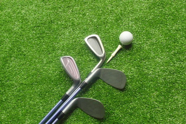 Golf topları ve golf kulüpleri yeşil çimenler üzerinde. Üst görünümde golf ekipmanları. Dünyanın dört bir yanındaki insanların sağlık için tatillerde oynadığı sporlar.