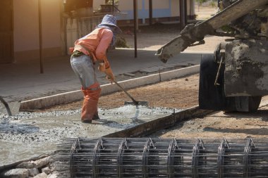 İşçiler çimento karıştırıcı kamyonuyla beton döküyorlar. Yol inşaatı veya genel yüzey onarımı