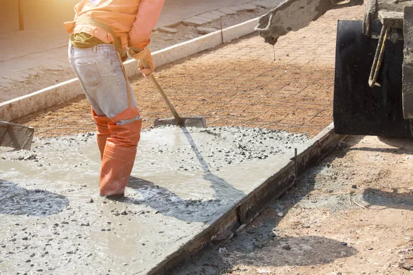 İşçiler çimento karıştırıcı kamyonuyla beton döküyorlar. Yol inşaatı veya genel yüzey onarımı