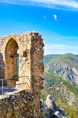 Kuzey Kıbrıs'taki Saint Hilarion Kalesi'nin kalıntılarını yakalayan dikey fotoğraf. Popüler manzara, güzel Girne bölgesi ve Akdeniz'in muhteşem manzarasını sunmaktadır. Kıbrıs turistik