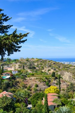 Girne bölgesinde inanılmaz kıyı manzara dikey resim, Kuzey Kıbrıs. Yeşil ağaçlarla çevrili kırsal evler Akdeniz'e bakmaktadır. Popüler tatil yeri