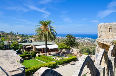 Bellapais, Kıbrıs - 4 Ekim 2018: Kıbrıs'ın Bellapais kentindeki ortaçağ bellapais manastırının kalıntılarından manzara. İç avluda turistler için güzel Akdeniz manzarası ve açık kafe