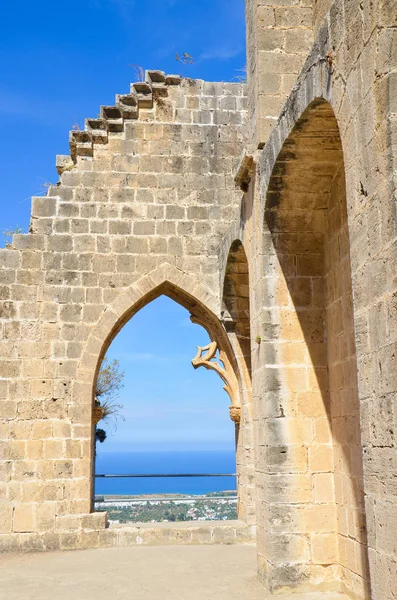 Ruínas das muralhas da histórica Abadia de Bellapais com uma janela que oferece uma bela vista da região cipriota da Cirenia. A vista popular está com vista para o Mediterrâneo na parte turca de Chipre — Fotografia de Stock