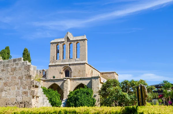 Amazing front side of ancient Bellapais Abbey in Turkish Northern Cyprus captured with the adjacent park and with blue sky. The ruins of the monastery are popular with tourists — Stock Photo, Image