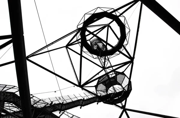Fotografia em preto e branco da impressionante construção em aço do Tetraedro em Bottrop, aa Alemanha tirada de baixo contra o céu. A impressionante estrutura walkable serve como um ponto de vista popular — Fotografia de Stock