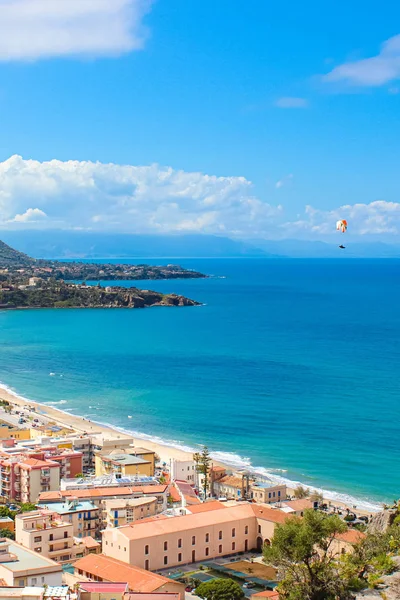 이탈리아 세팔루의 아름다운 푸른 만 위로 날아다니는 패러글라이더, 시칠리아는 수직 사진으로 촬영했습니다. 패러글라이딩은 인기 있는 어드벤처 스포츠입니다. 세팔루는 티레니아 해안에 위치해 있습니다. — 스톡 사진