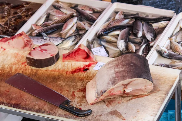 Részlet a szeletelt elhullott halakat egy fából készült asztal nagy fejsze. Más elpusztult halak elmosódnak a háttérben. Állatvédelmi koncepció. Halászat, orvvadászat, illegális vadászati. Globális probléma — Stock Fotó
